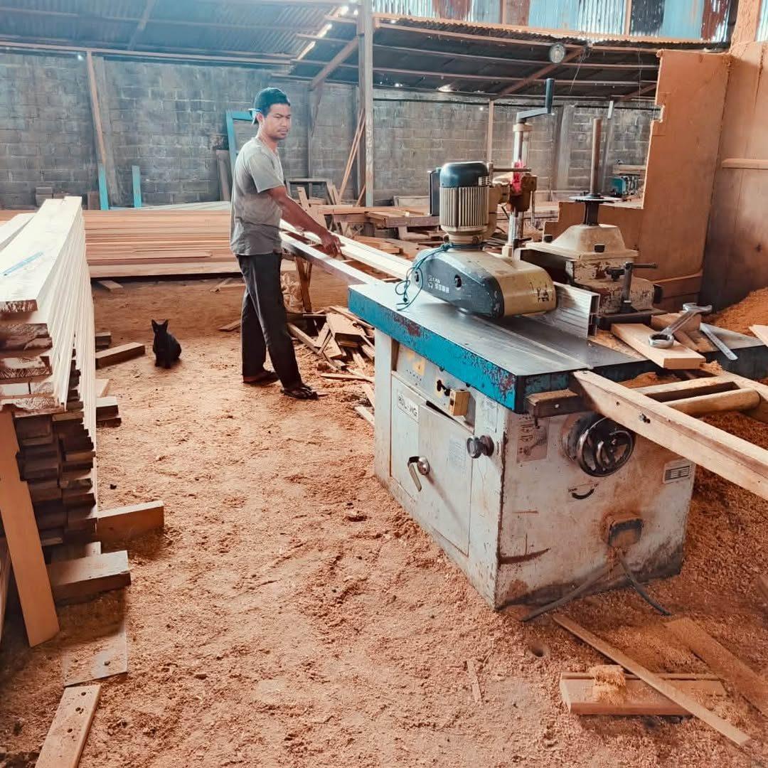 Menuisier rabotant des planches dans l'atelier bois